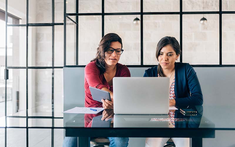 Two women discussing matters in front of a laptop